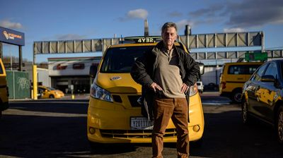 a man standing in front of a yellow taxi