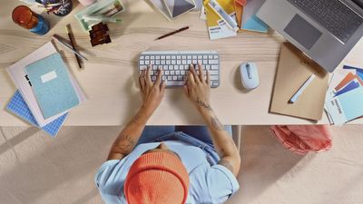 a person sitting at a desk with a keyboard and mouse