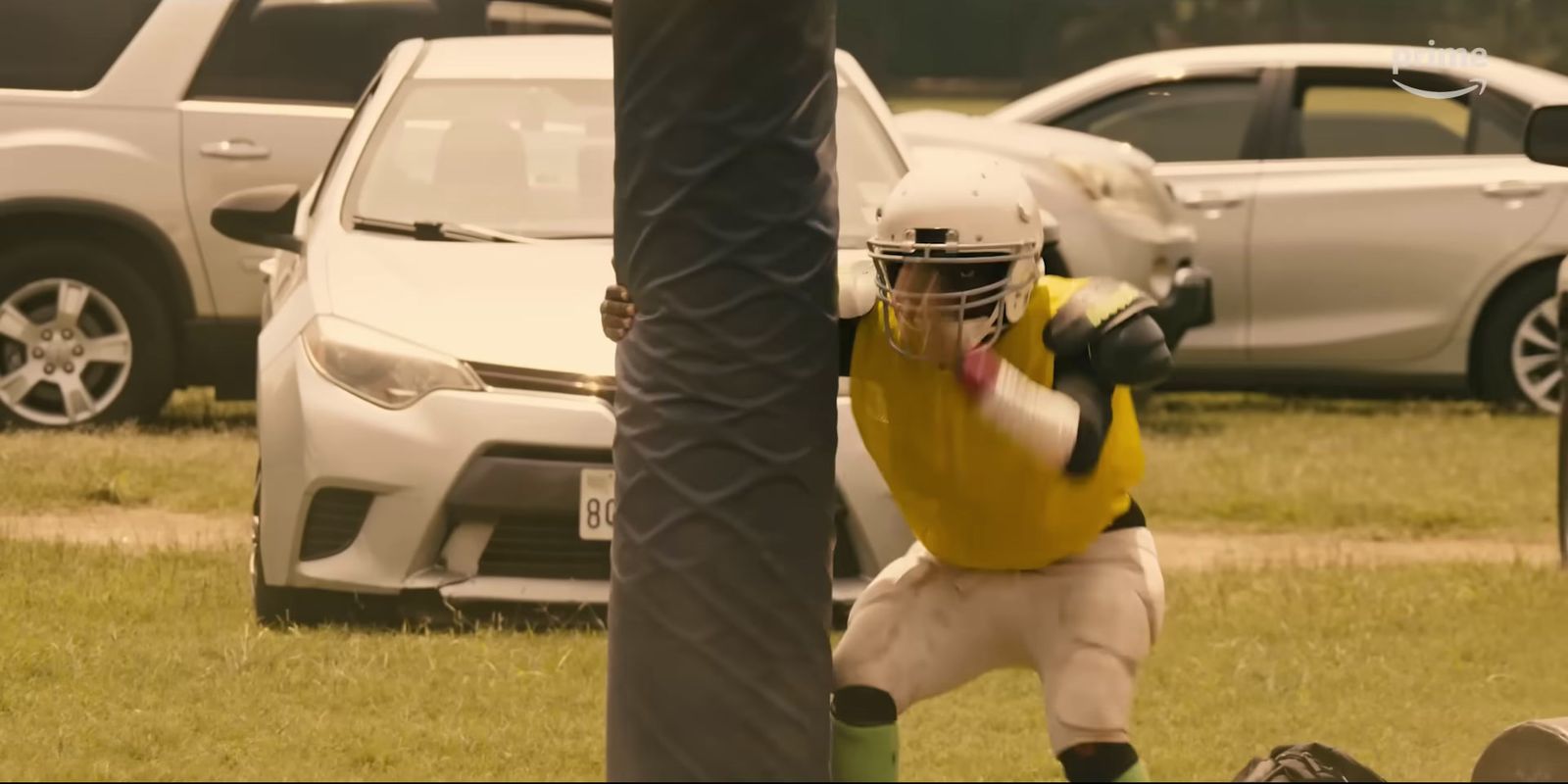 a man in a yellow shirt and helmet holding a baseball bat