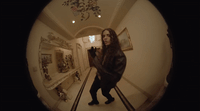 a woman in a black jacket is taking a picture of herself in a mirror