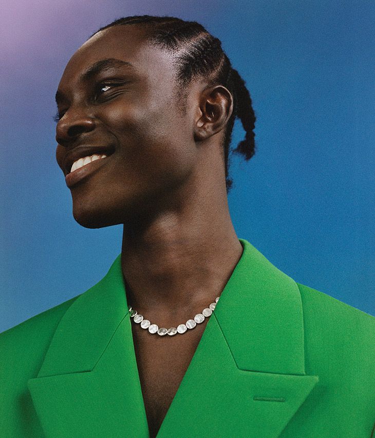 a woman in a green suit with a pearl necklace