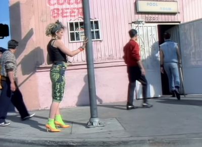 a woman standing on a street corner next to a pole