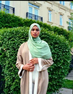 a woman in a hijab standing on a sidewalk