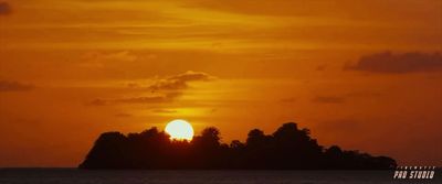 the sun is setting over a small island