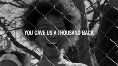 a black and white photo of a woman behind a fence