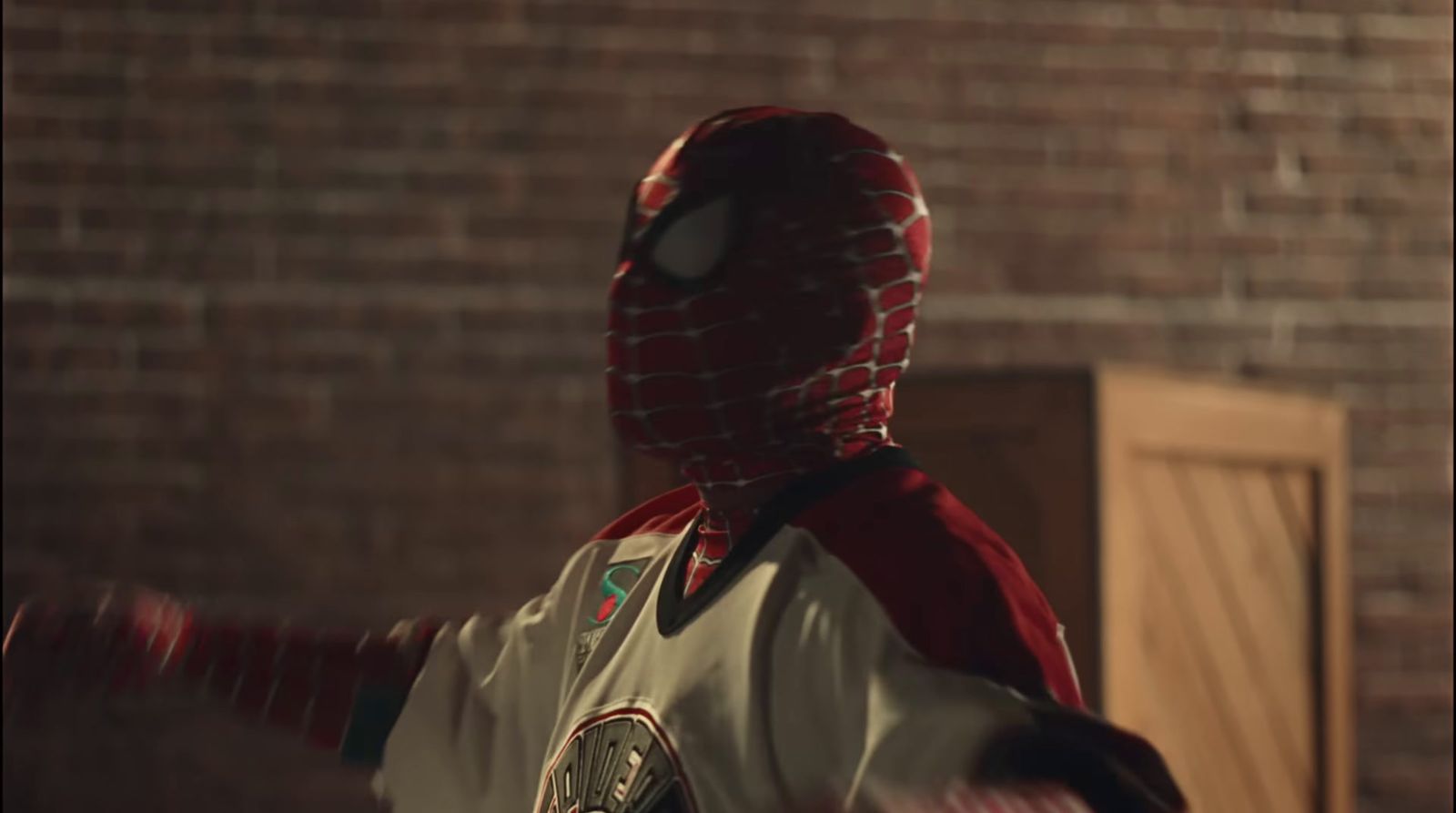 a man in a spider - man costume standing in front of a brick wall