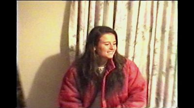 a woman in a red jacket standing in front of a window