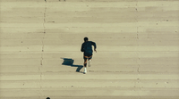 a man is running on the beach with a surfboard