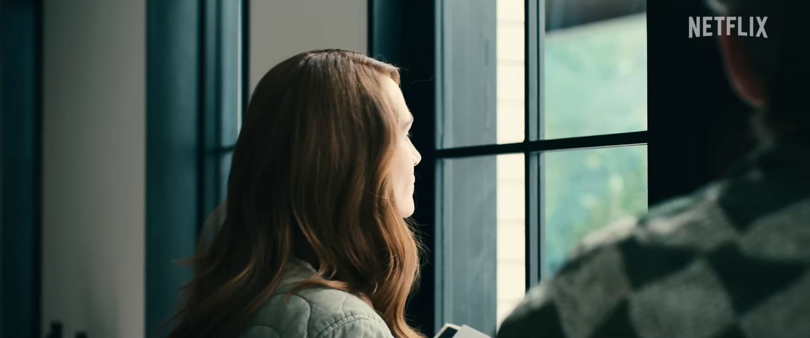 a woman looking out a window at a man