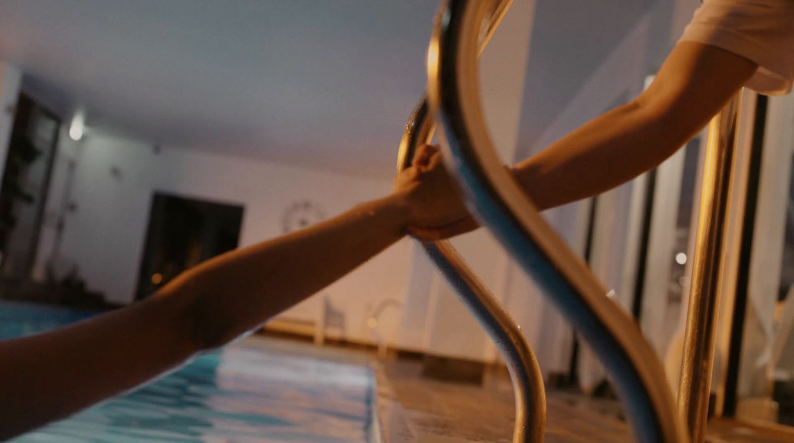 a person holding onto a metal railing near a swimming pool