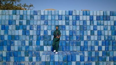 a man standing in front of a wall made of blue tiles