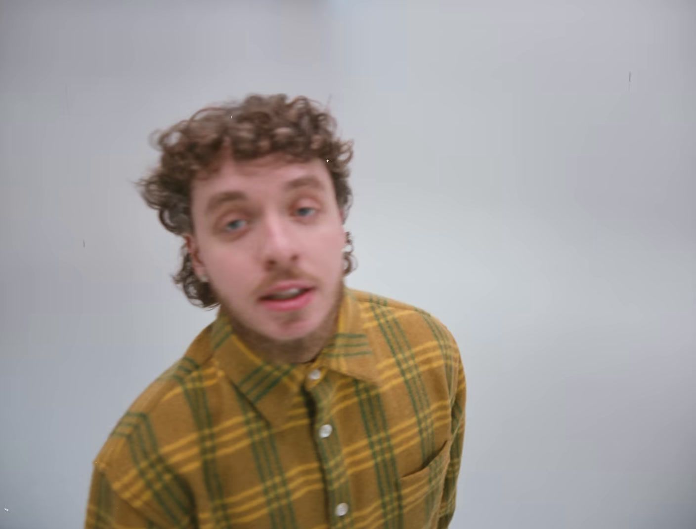 a man with curly hair wearing a yellow shirt