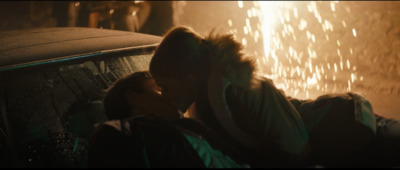 a man and a woman kissing in front of a car