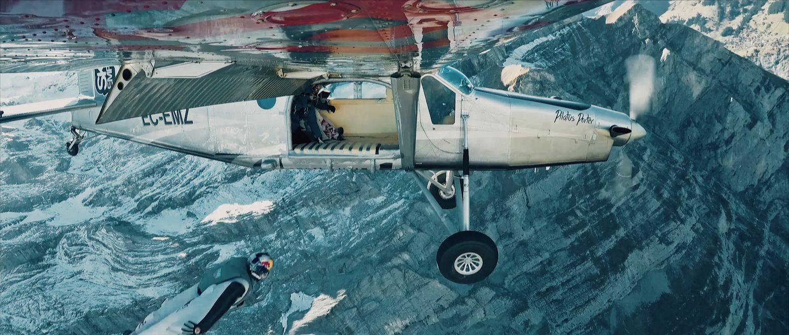a small airplane flying over a mountain side