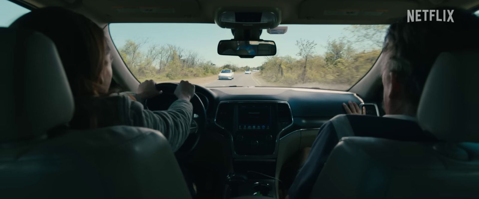 a man driving a car down a road next to a forest