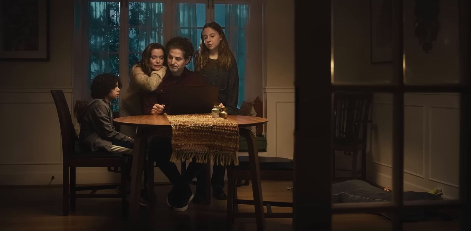 a group of people sitting around a table looking at a laptop