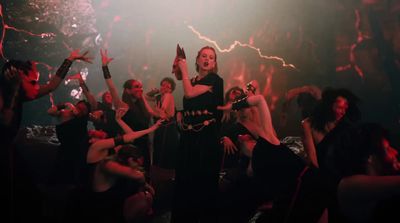 a woman in a black dress standing in front of a crowd of people