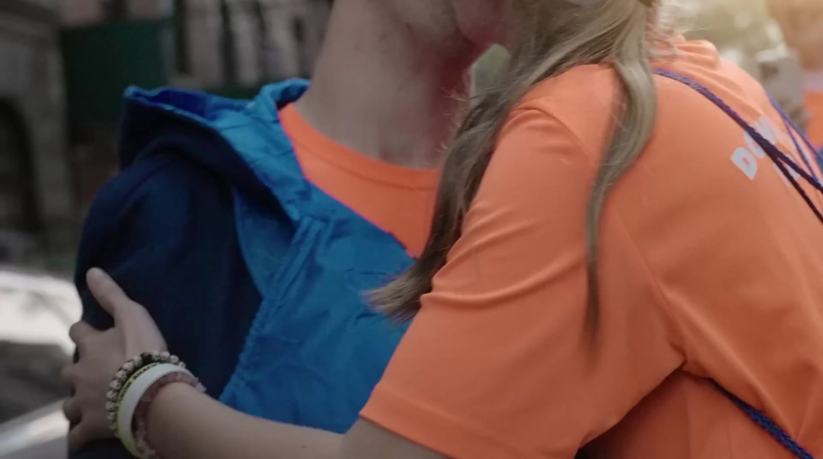 a woman in an orange shirt and a blue backpack