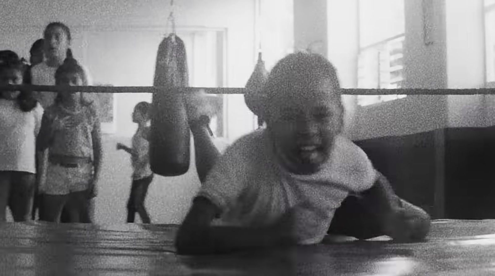 a young boy is laying on the ground in a boxing ring