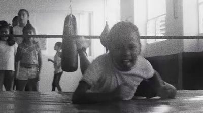 a young boy is laying on the ground in a boxing ring