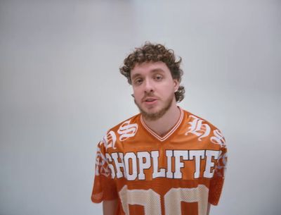 a man with curly hair wearing an orange football jersey