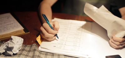 a person sitting at a table writing on a piece of paper