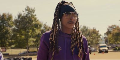 a man with dreadlocks standing in a parking lot