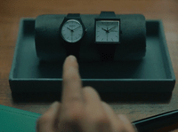 a person pointing at two clocks on a table