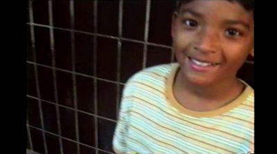 a young boy smiling in front of a tiled wall