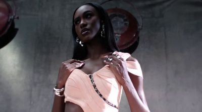 a woman in a pink dress standing in front of a wall