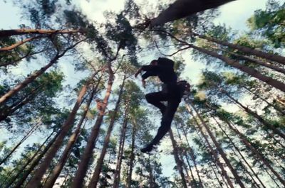 a man is suspended in the air in the middle of a forest