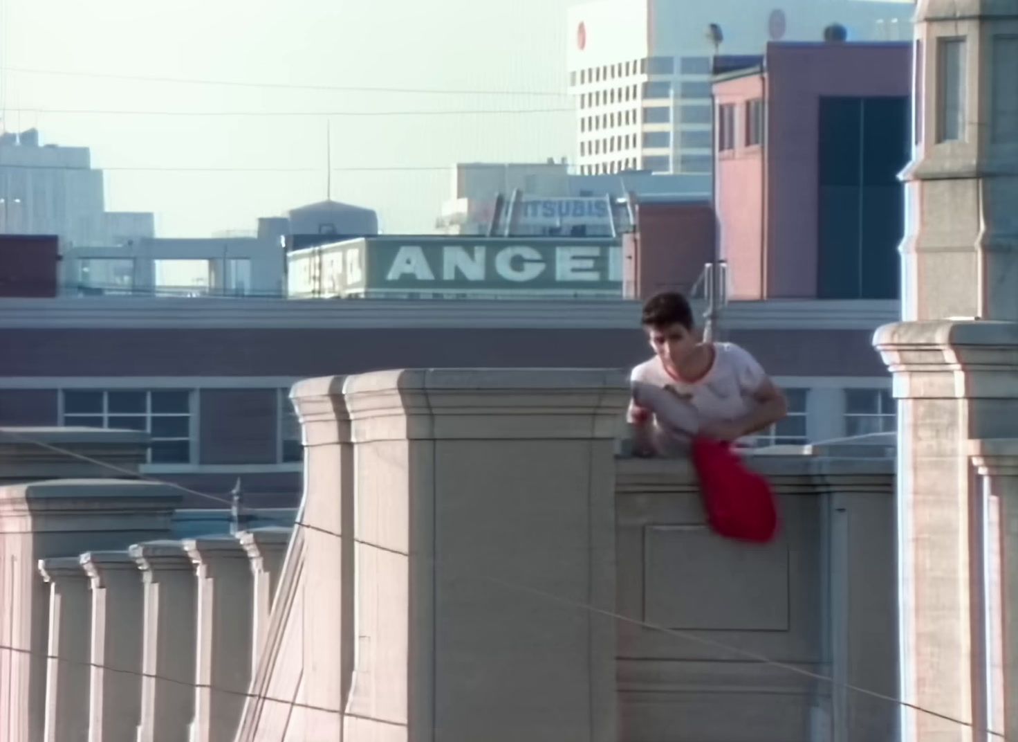 a woman is standing on a ledge in a city