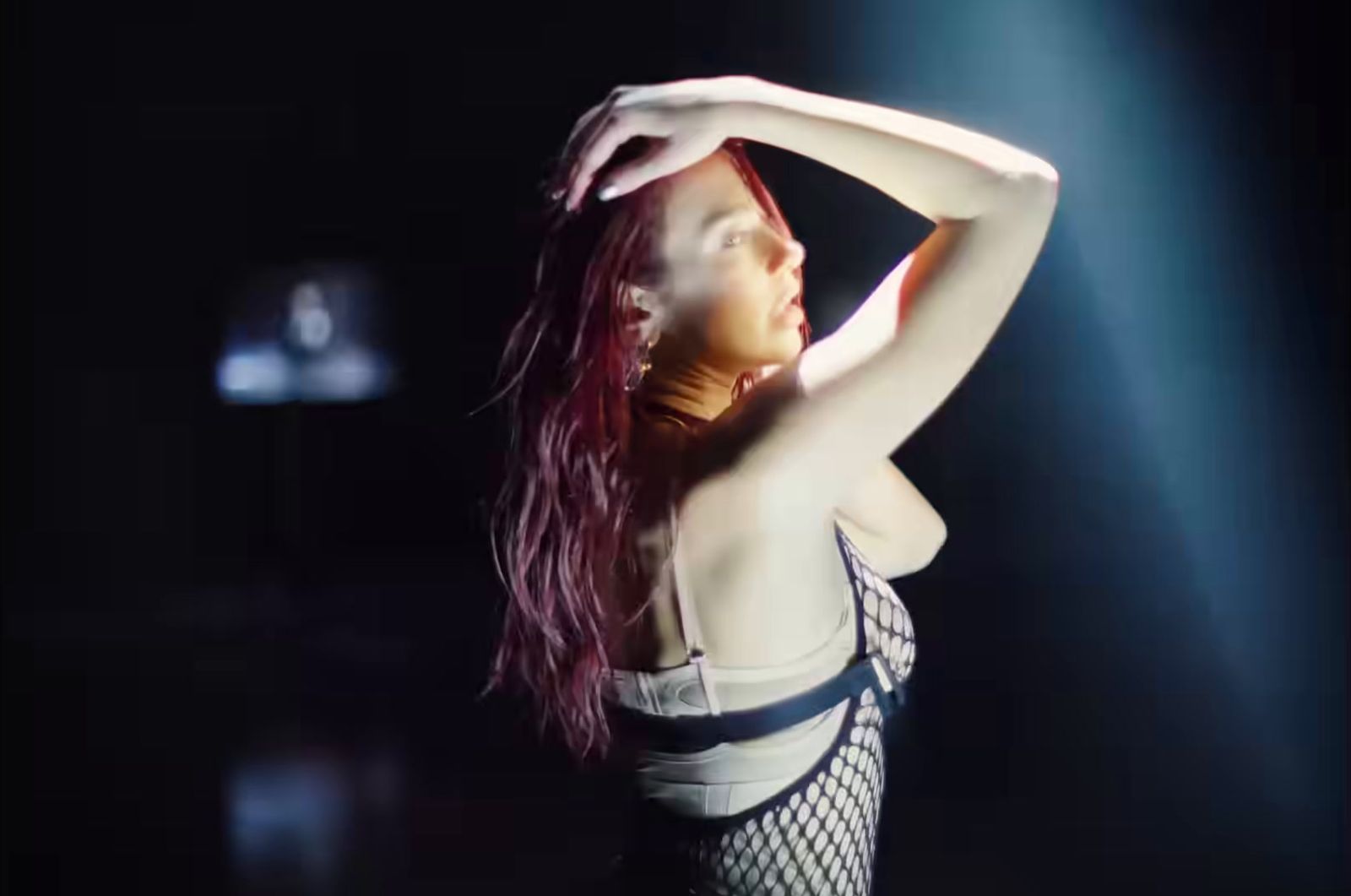 a woman in a fishnet bodysuit dancing in the dark