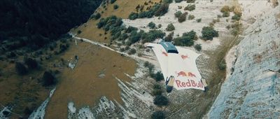 a red bull airplane is flying over a mountain