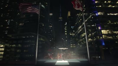 a city street at night with tall buildings and american flags