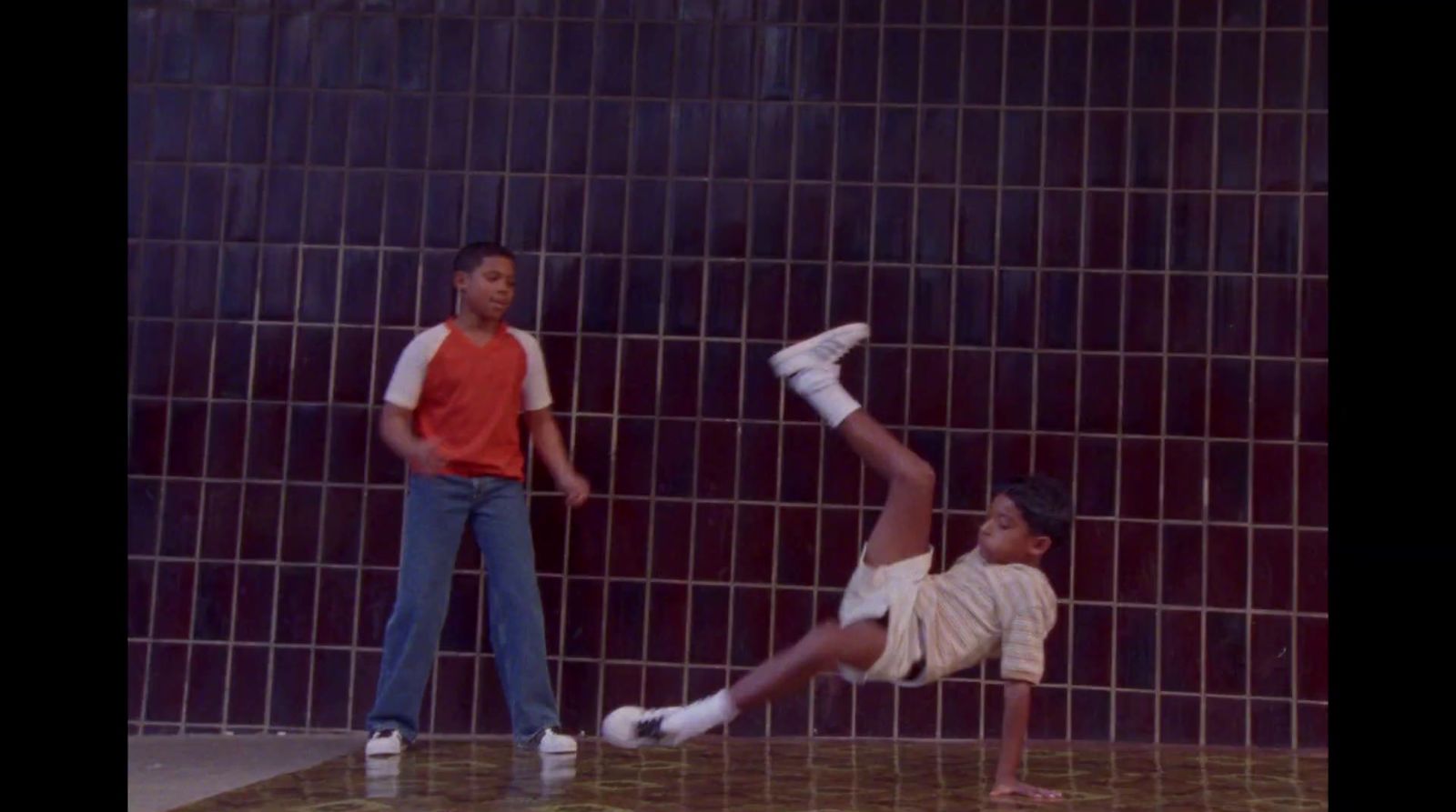 a young boy doing a handstand in front of a tiled wall