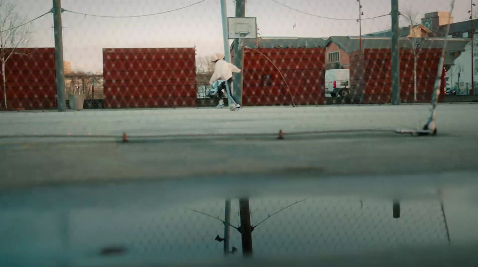 a man riding a skateboard down a street next to a fence