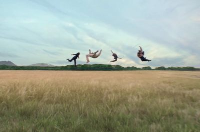 three people jumping in the air in a field