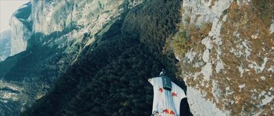 a man standing on top of a cliff next to a mountain