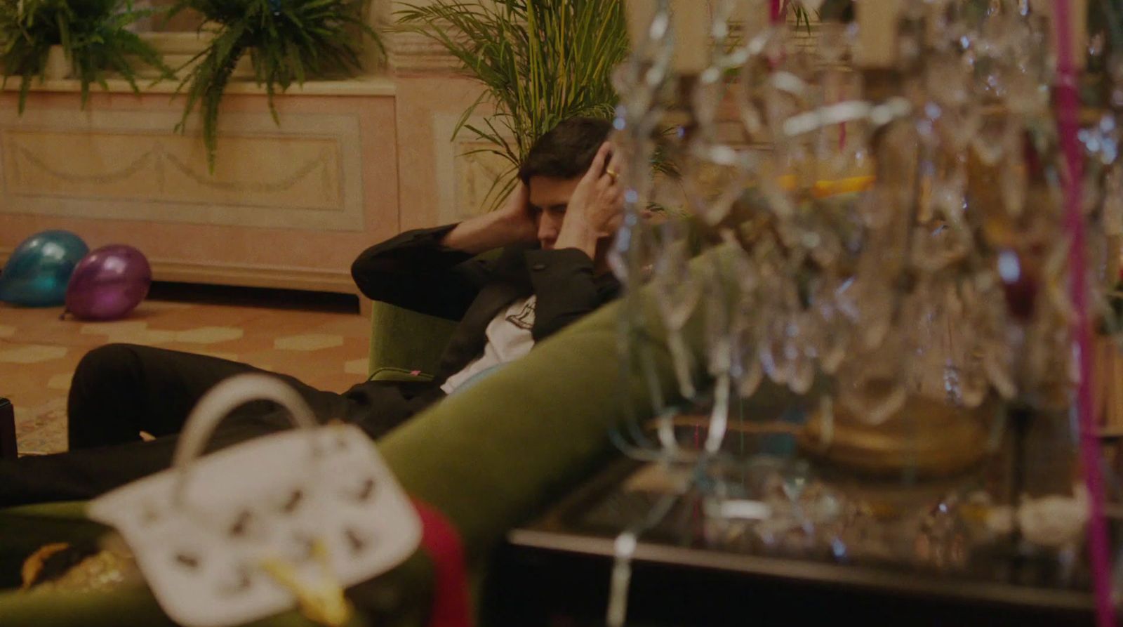 a man sitting on a couch in a room filled with wine glasses