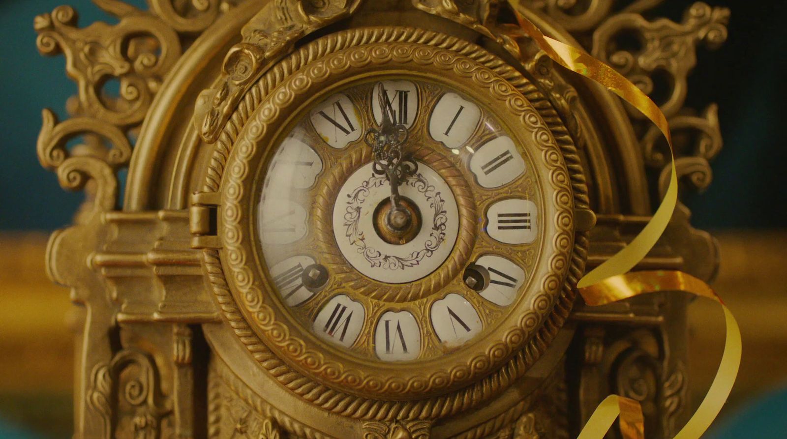 a gold clock with a gold ribbon around it