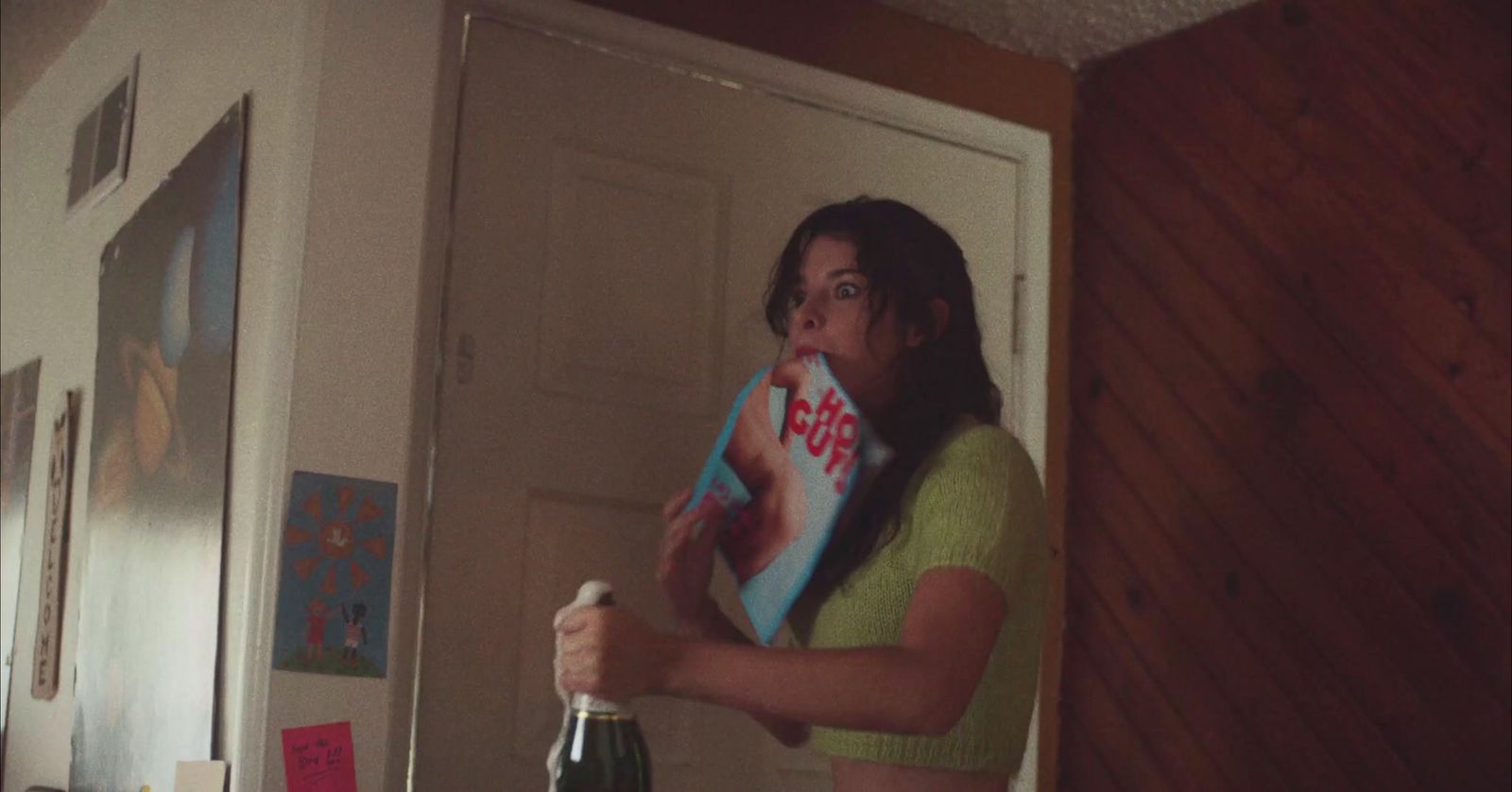 a woman standing in a room holding a bottle of wine