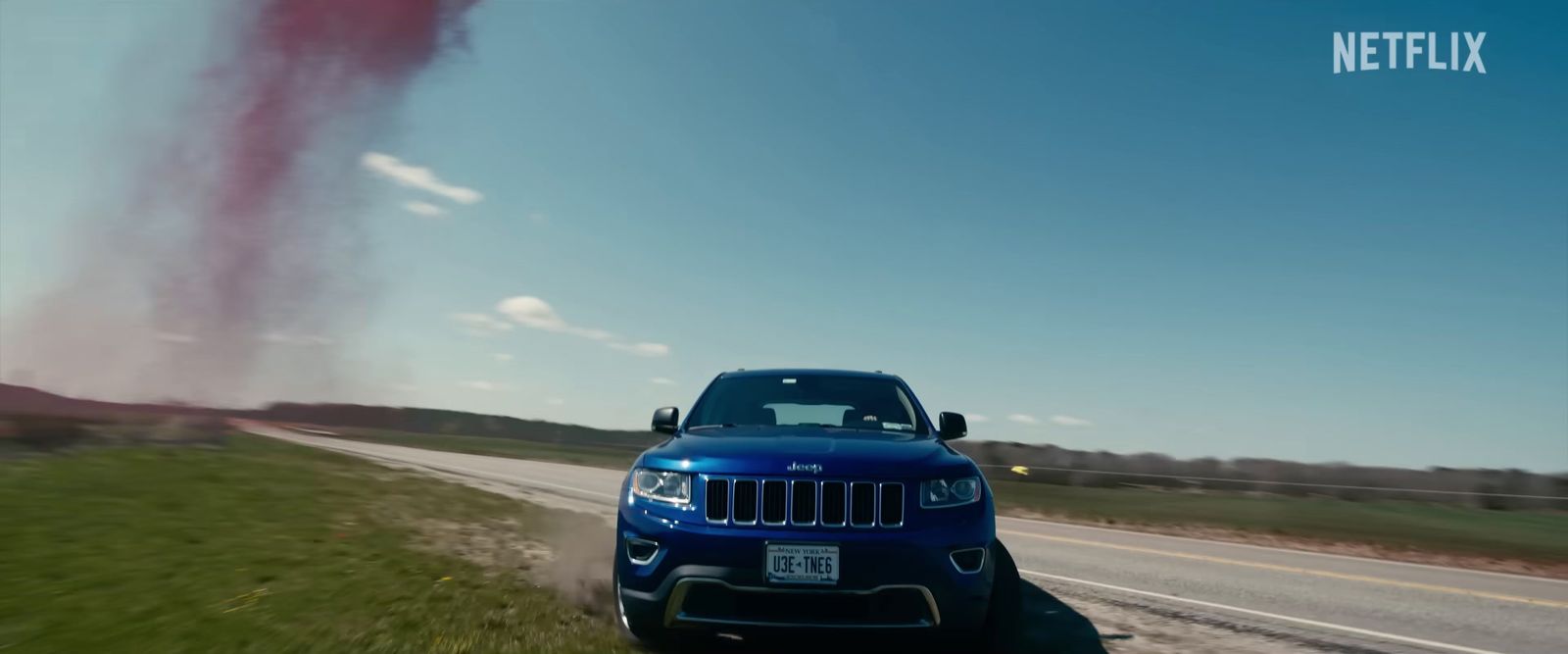 a blue jeep driving down a country road