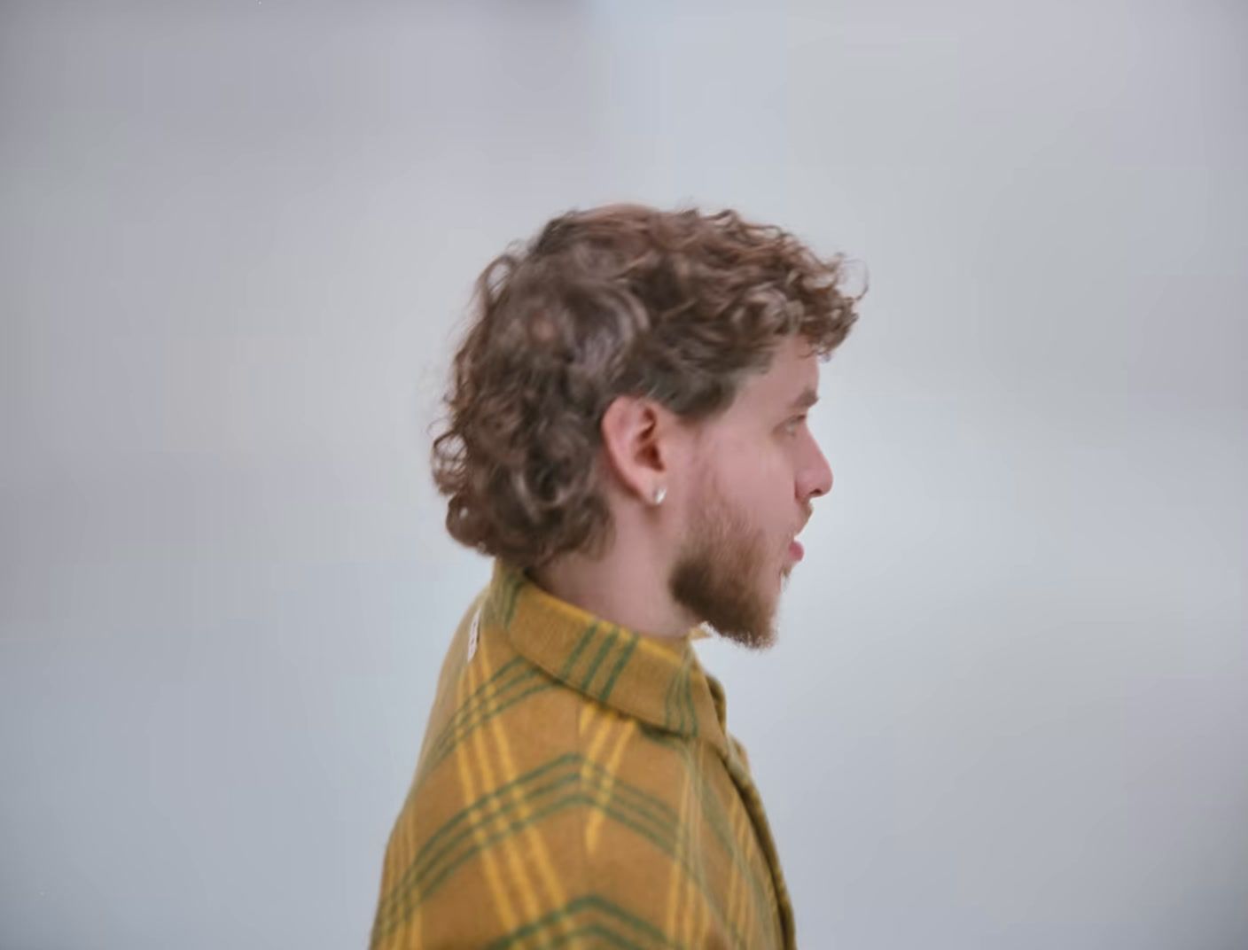 a man with curly hair wearing a yellow shirt