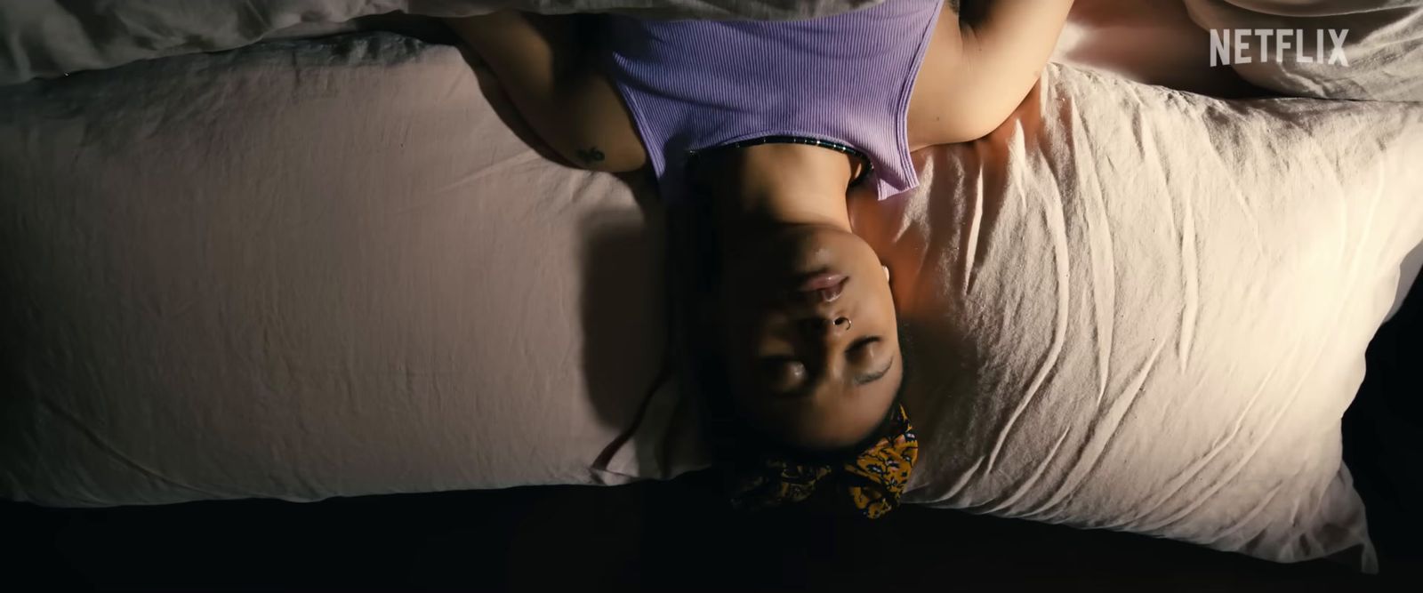 a person laying on a bed with their head on a pillow