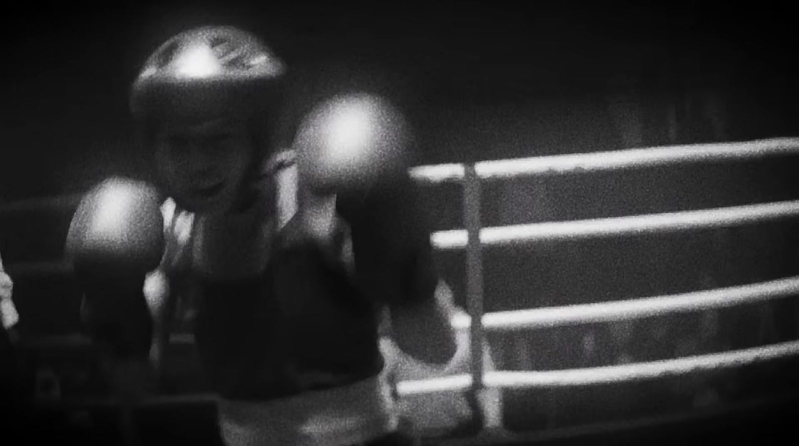 a black and white photo of a young boy wearing boxing gloves