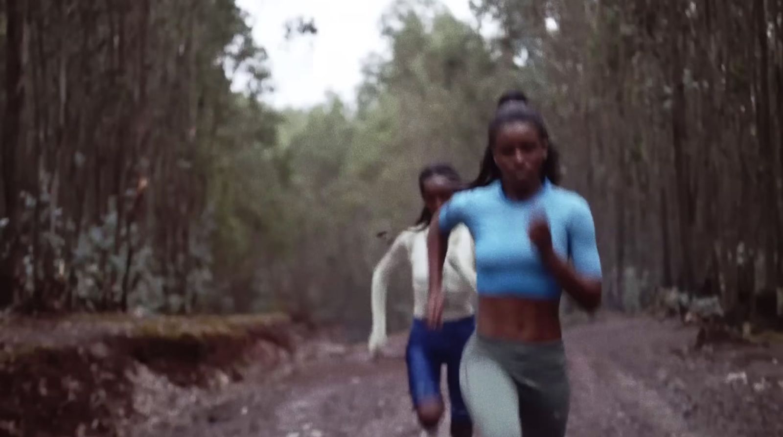 two women running down a dirt road in the woods