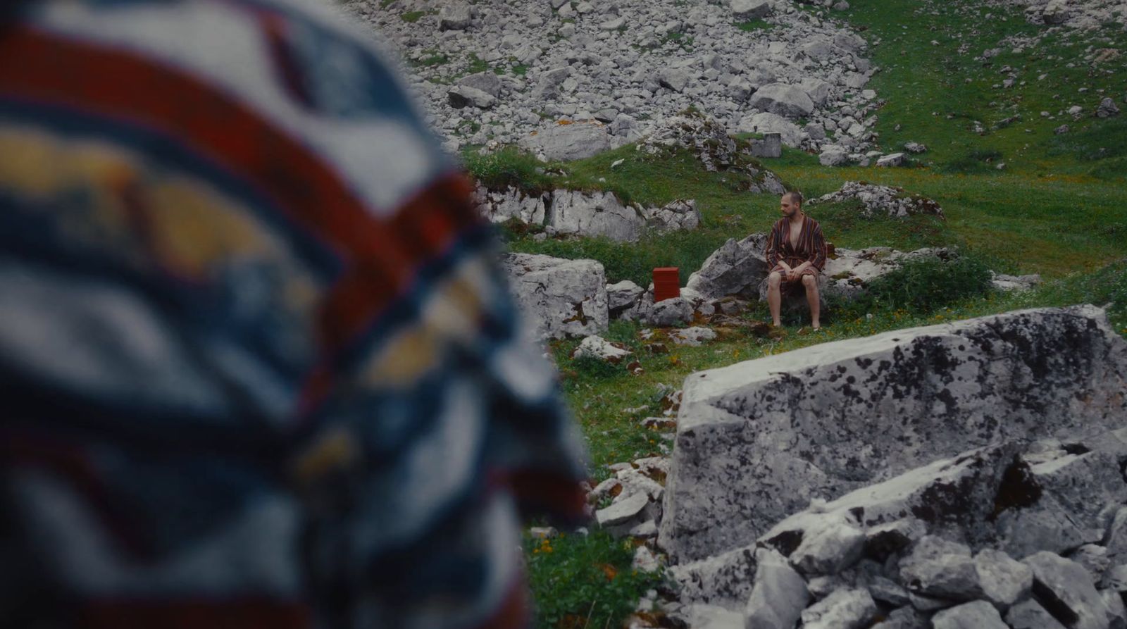 a man sitting on a rock in the middle of a field