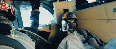 a man wearing a helmet and goggles sitting in a plane