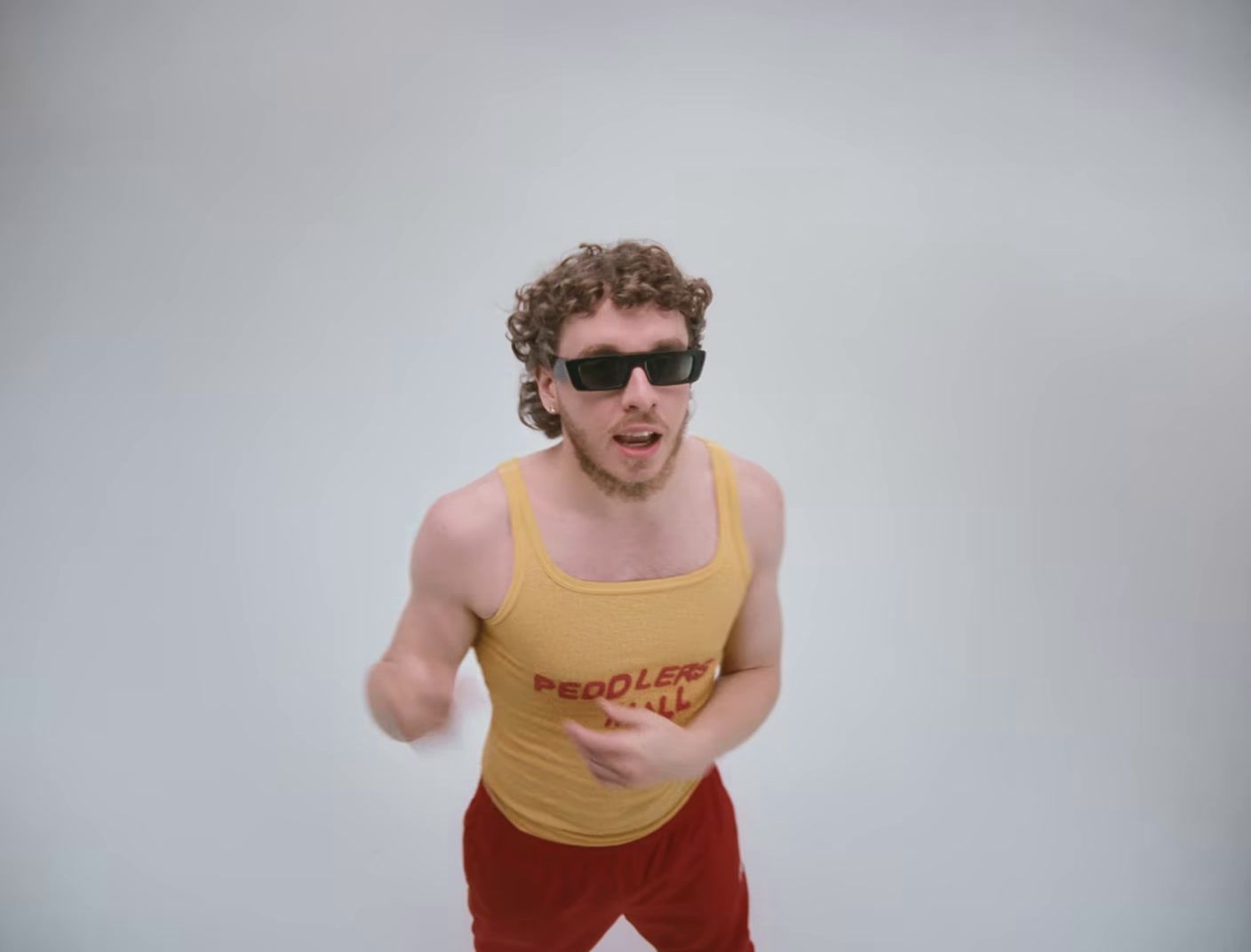 a man in a yellow tank top and red pants